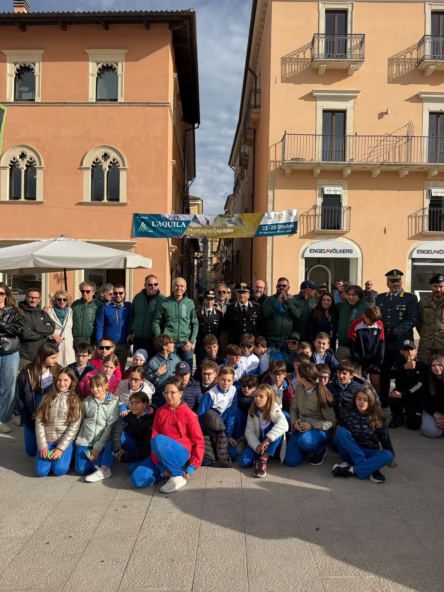 Ragazzi seduti in Piazza Duomo con adulti e rappresentanti delle forze dell’ordine alle loro spalle